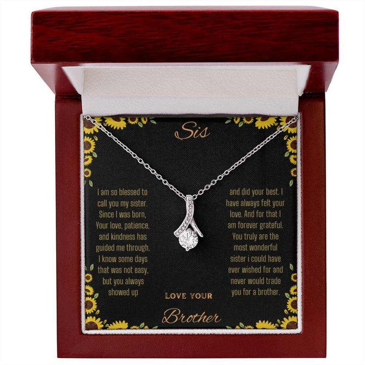 Alluring Beauty Necklace with a white gold variant on a To Sis from Brother greeting card inside a mahogany close up view