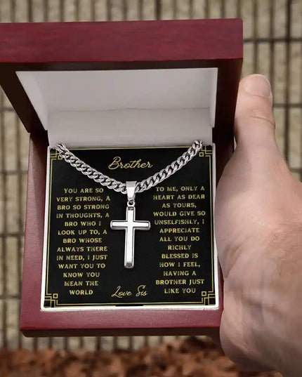 A artisan cross personalized cuban link chain in a mahogany box with a to brother greeting card in a models hand