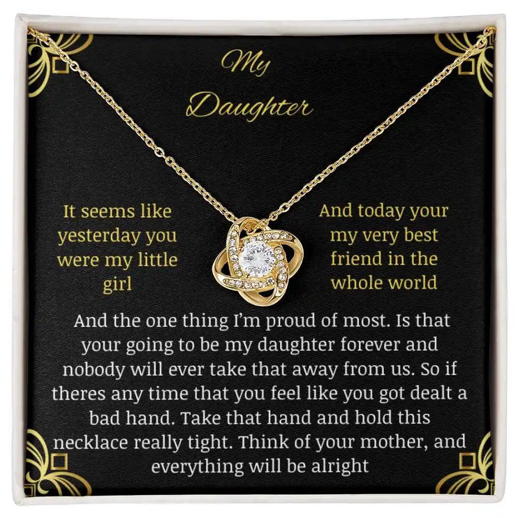Love Knot Necklace with a yellow gold charm in a two-tone box with a to daughter from mom greeting card close up