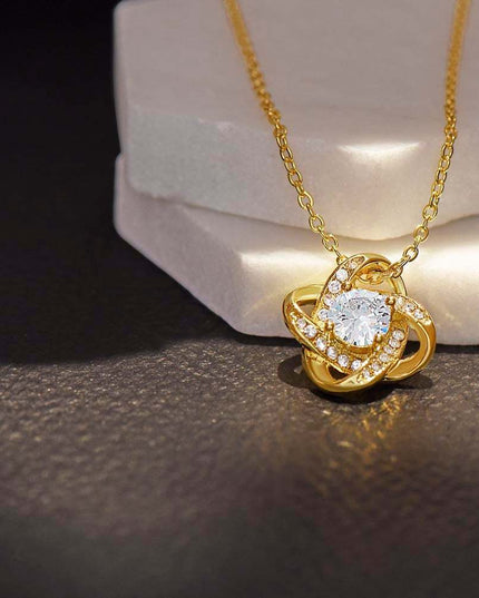 yellow gold love knot necklace on a display