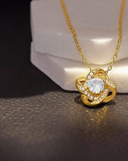 yellow gold love knot necklace on a white display