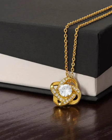 yellow gold love knot necklace on top of two-tone box