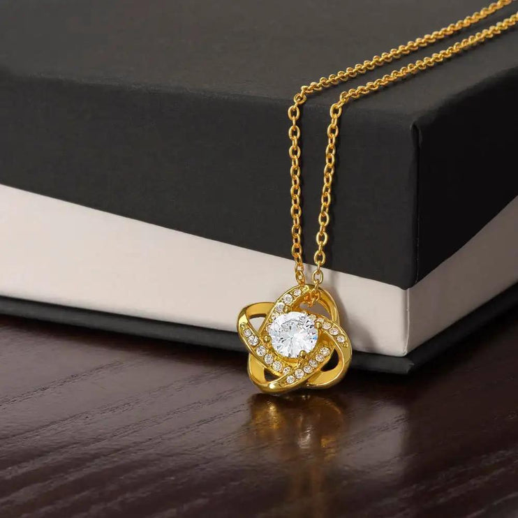 yellow gold love knot necklace on top of two-tone box