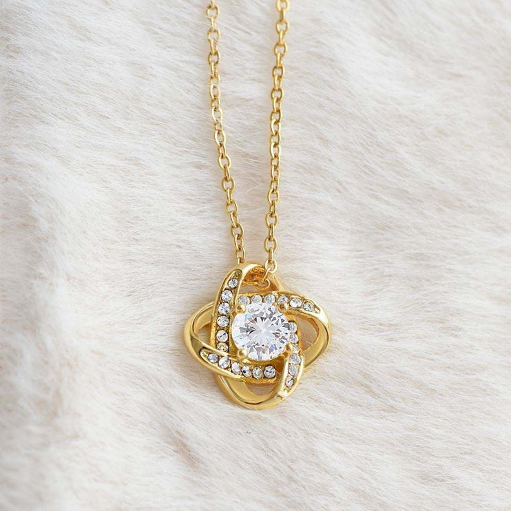 18k gold love knot necklace on a white plush cloth