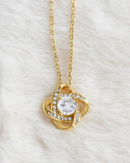 yellow gold love knot necklace on a white fleece
