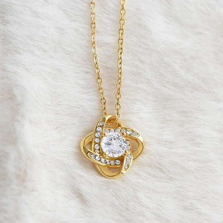 yellow gold love knot necklace on white fleece