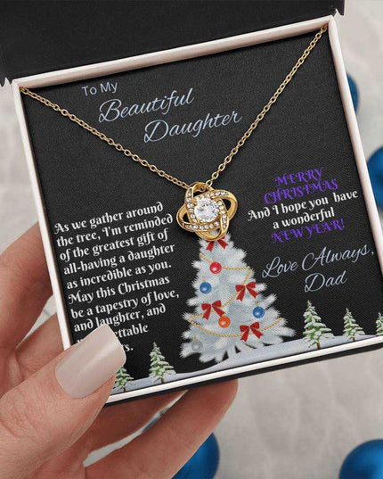 yellow gold love knot necklace in soft box in a model's hand