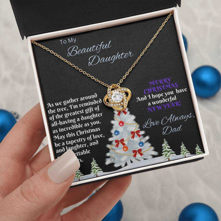 yellow gold love knot necklace in soft box in a model's hand