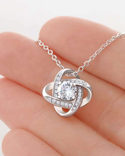 14k white gold love knot necklace in a model's hand