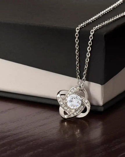 white gold love knot necklace on top of a two-tone box