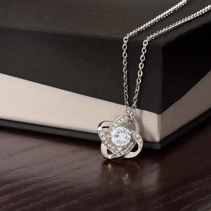 white gold love knot necklace on top of a two-tone box