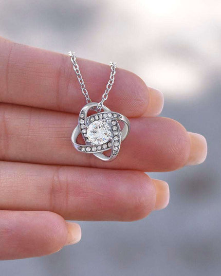 14k white gold love knot necklace in model's hand