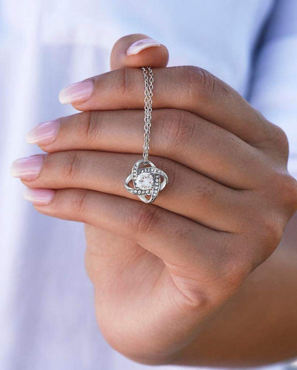white gold love knot necklace in model's hand