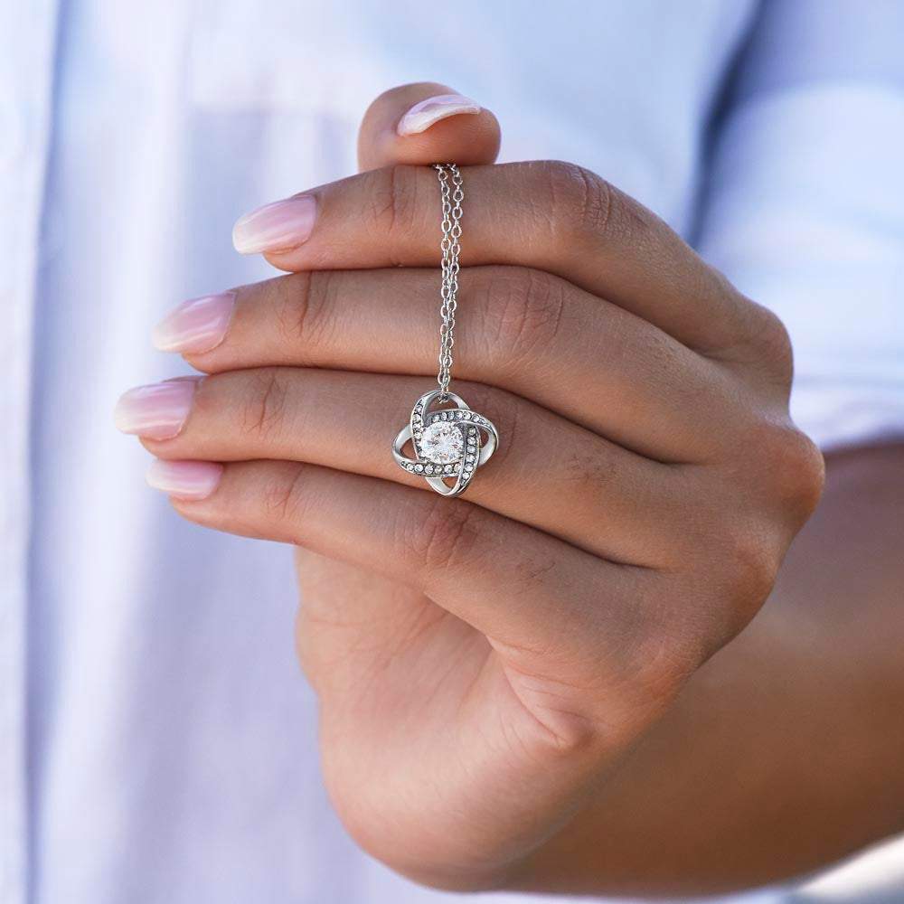 white gold love knot necklace in model's hand