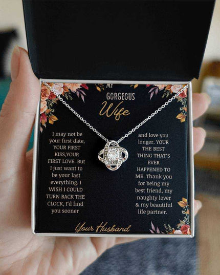 A white gold love knot necklace on a to wife greeting card in a models hand