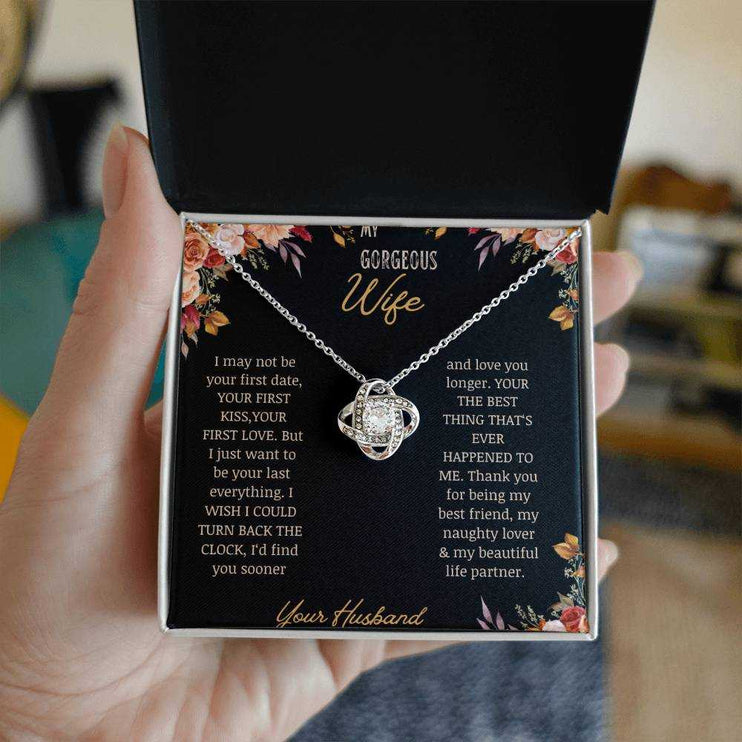 A white gold love knot necklace on a to wife greeting card in a models hand