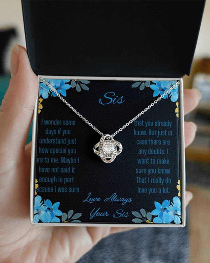 Love Knot Necklace with a white gold variant on a To Sis from Sis greeting card close up view in a models hand