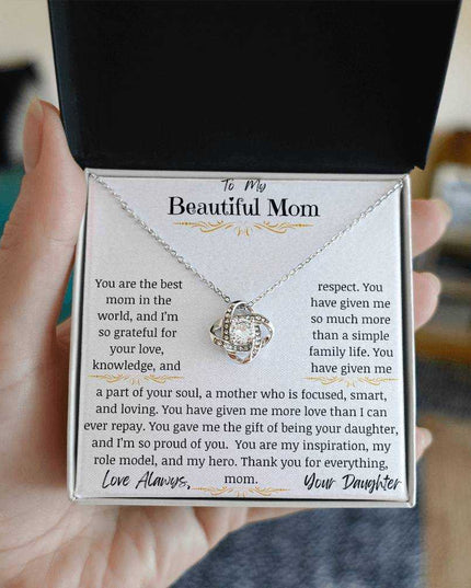 a white gold love knot necklace in models hand