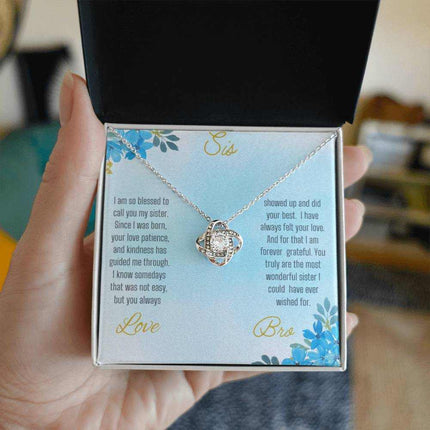 Love Knot Necklace with a white gold pendant on a To Sis from Bro greeting card inside of a two-tone box close view