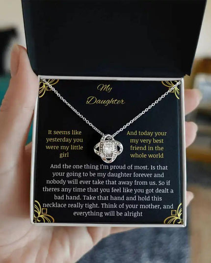 Love Knot Necklace with a white gold charm in a two-tone box with a to daughter from mom greeting card held in hand and away from