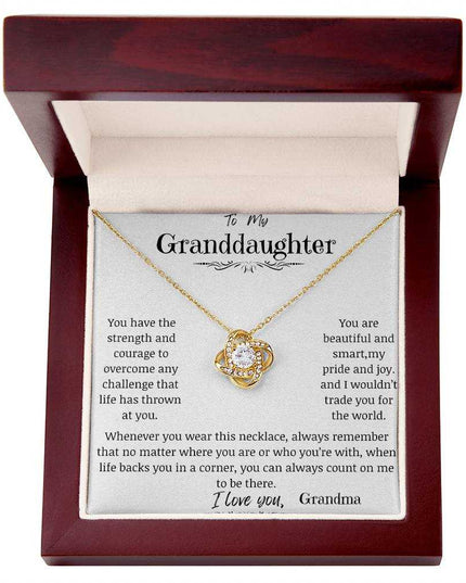 a yellow gold love knot necklace up close in a mahogany box