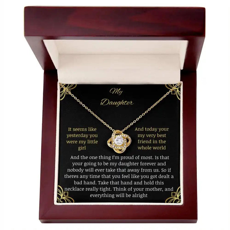 Love Knot Necklace with a yellow gold charm in a mahogany box with a to daughter from mom greeting card close up