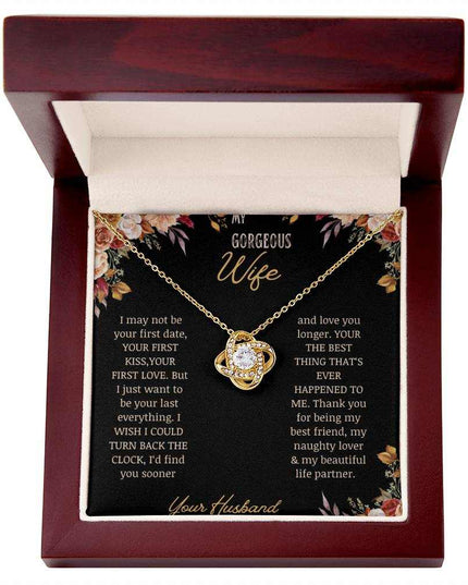 A yellow gold love knot necklace on a to wife greeting card in a mahogany box