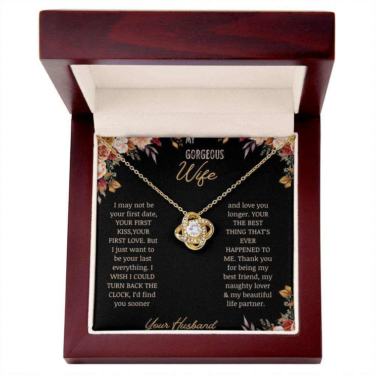 A yellow gold love knot necklace on a to wife greeting card in a mahogany box