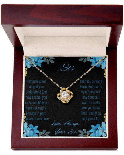 Love Knot Necklace with a yellow gold variant on a To Sis from Sis greeting card close up in a mahogany box