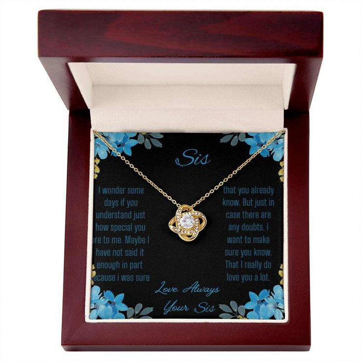 Love Knot Necklace with a yellow gold variant on a To Sis from Sis greeting card close up in a mahogany box