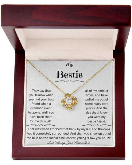 a yellow gold love knot necklace up close in a mahogany box.