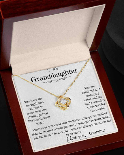 a yellow gold love knot necklace up close in a mahogany box angled left
