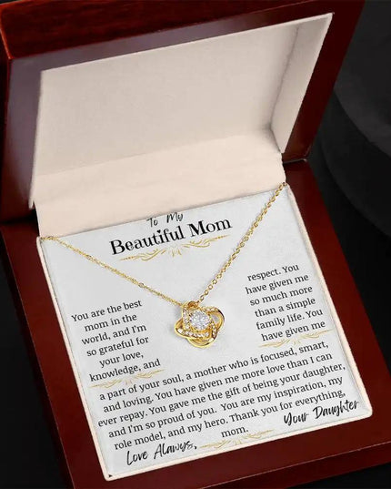 a yellow gold love knot necklace up close in a mahogany box angled left