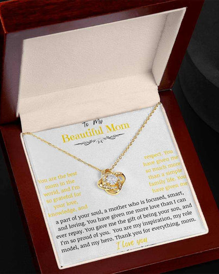 A yellow gold love knot necklace in a mahogany box angled to left
