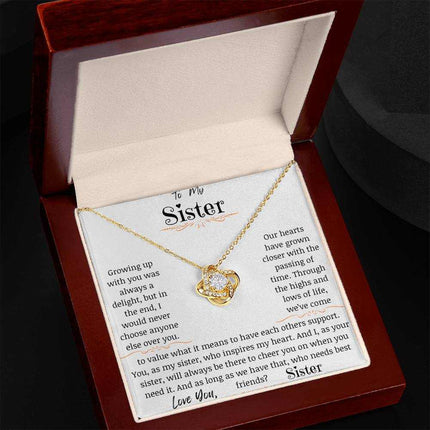 a yellow gold love knot necklace in a mahogany box angled to right.