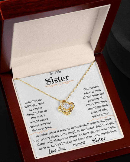 a yellow gold love knot necklace in a mahogany box angled to right.