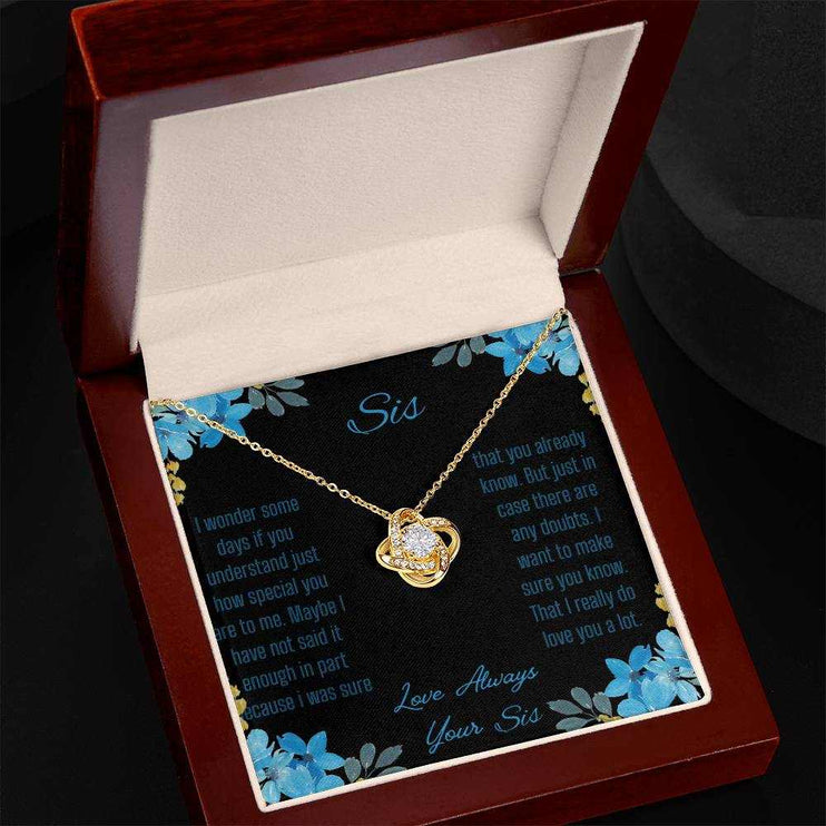 Love Knot Necklace with a yellow gold variant on a To Sis from Sis greeting card close up in a mahogany box angled to the left side