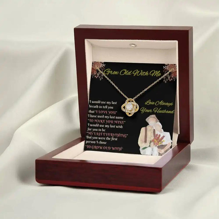 yellow gold love knot necklace in mahogany box on white cloth