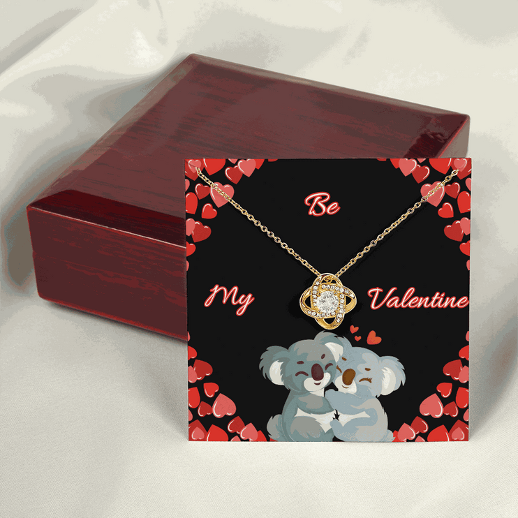18k gold love knot necklace on top of a closed luxury box
