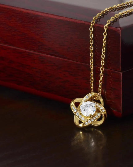 yellow gold love knot necklace on a mahogany box