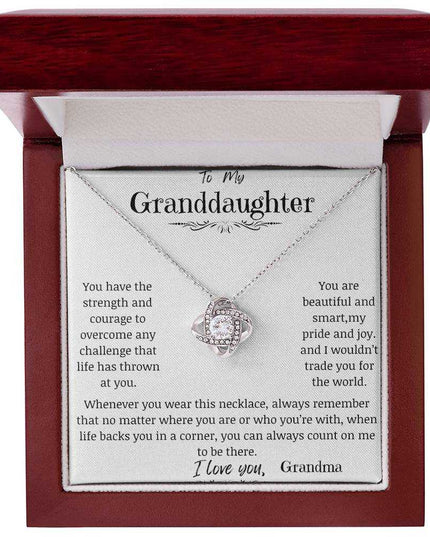 a white gold love knot necklace up close in a mahogany box