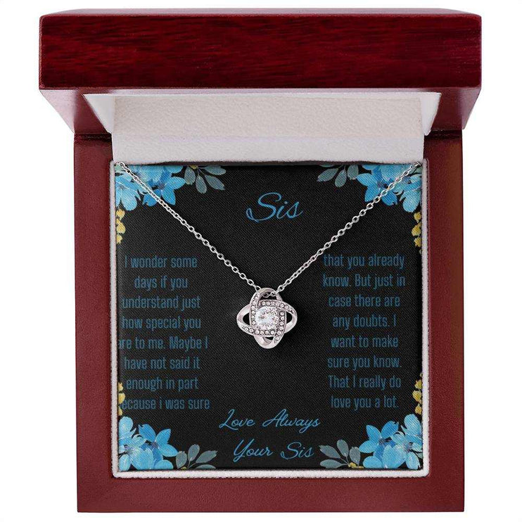 Love Knot Necklace with a white gold variant on a To Sis from Sis greeting card close up in a mahogany box