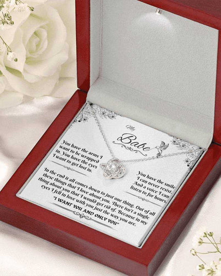 white gold love knot necklace in luxury box angled right with flowers