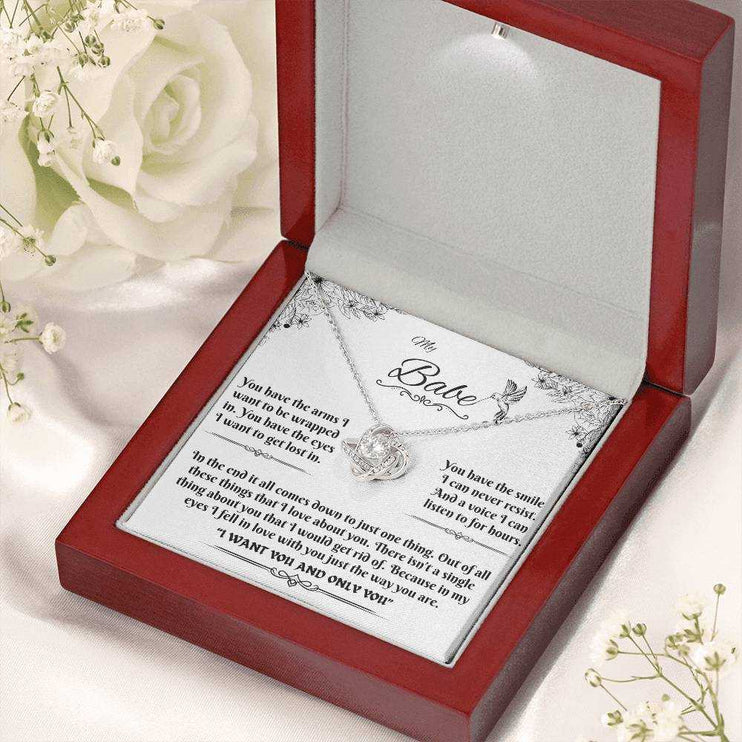 white gold love knot necklace in luxury box angled right with flowers