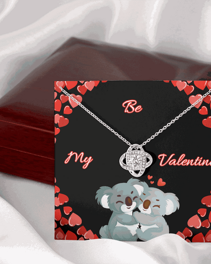 14k white gold love knot necklace on a card leaning on a mahogany box