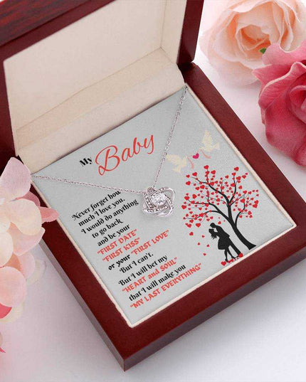 white gold love knot necklace in luxury box angled left with flowers