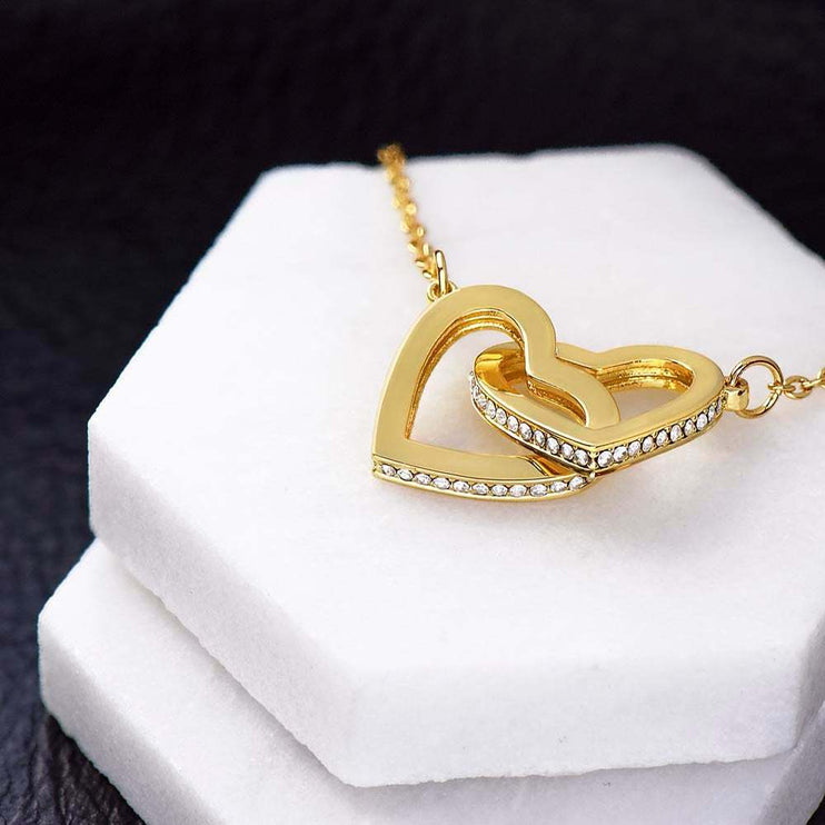 18k interlocking hearts necklace on a marble display