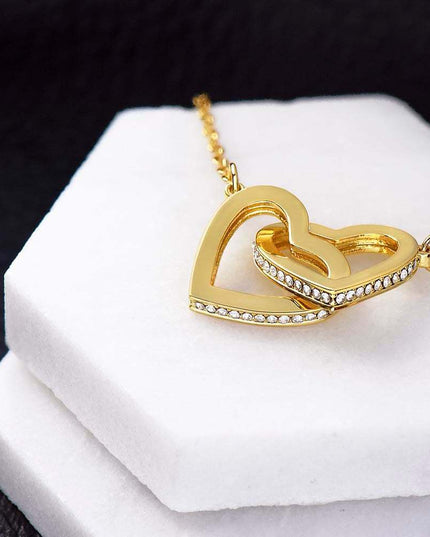 gold interlocking hearts necklace on a white display 
