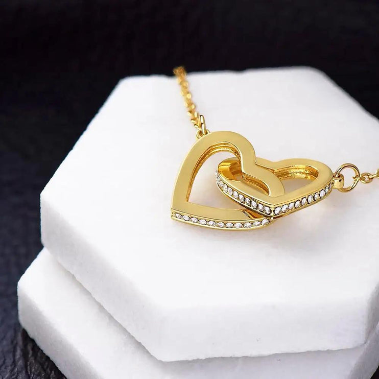 yellow gold interlocking hearts necklace on a white display