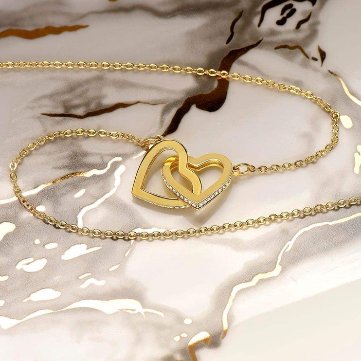gold interlocking hearts necklace on a marble counter top